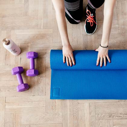 A woman rolling up a yoga mat after exercising